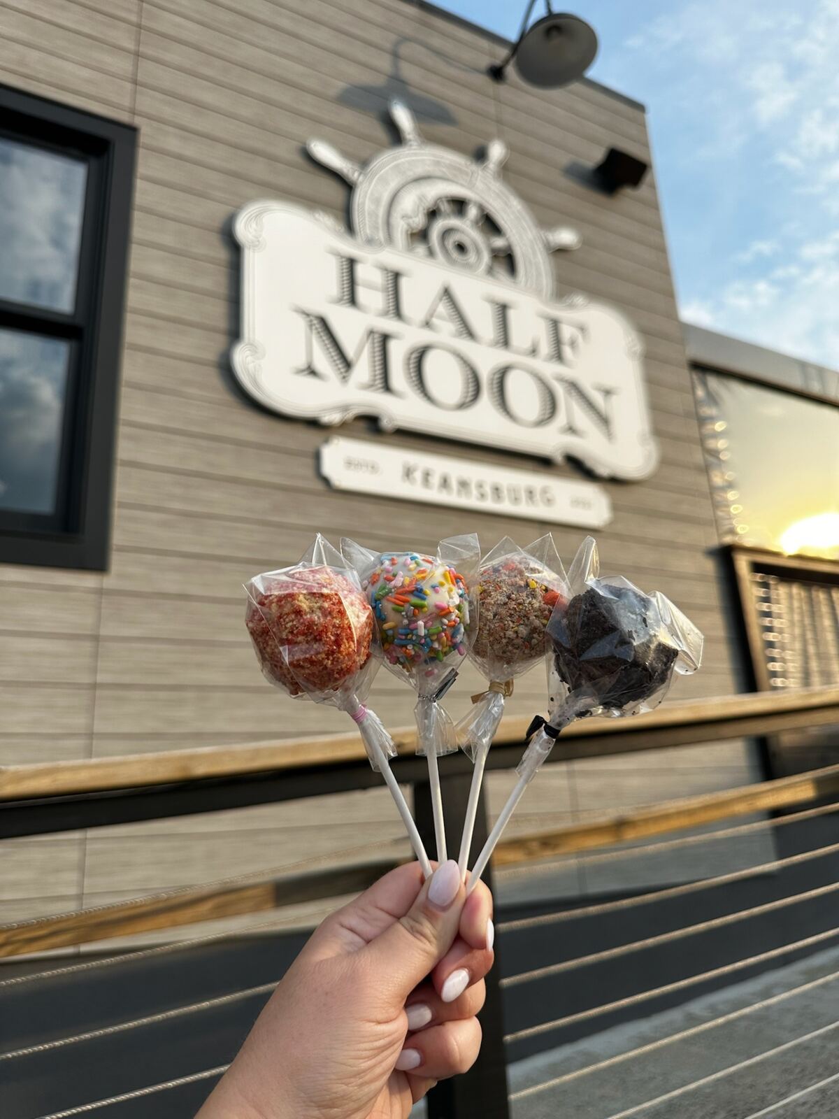 Cake pops in front of the Half Moon sign at sunset